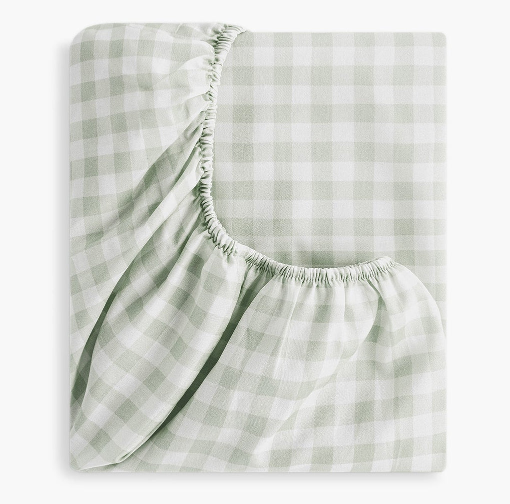 The Gooselings Green Picnic Gingham Crib Sheet features a light green and white check pattern, visible elastic corners, and is made from OEKO-TEX certified cotton sateen.