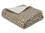 Folded quilt from the Matouk Gabriel Bedding Collection, featuring a brown and white geometric pattern on top and a solid off-white quilted underside, resting on a white background—an elegant example of luxury bed linen.