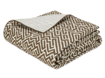 The Gabriel Bedding Collection, Mocha by Matouk features a folded quilt with a brown and white geometric motif on one side and a solid cream quilted design on the other, ideal for layering with Schumacher or woven tapestry bedding.
