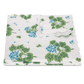 Folded Matouk Tillett x Matouk Geranium Bedding Collection in blue, featuring a white base with green leaves, blue floral pattern, and scalloped edges, displayed on a plain background.
