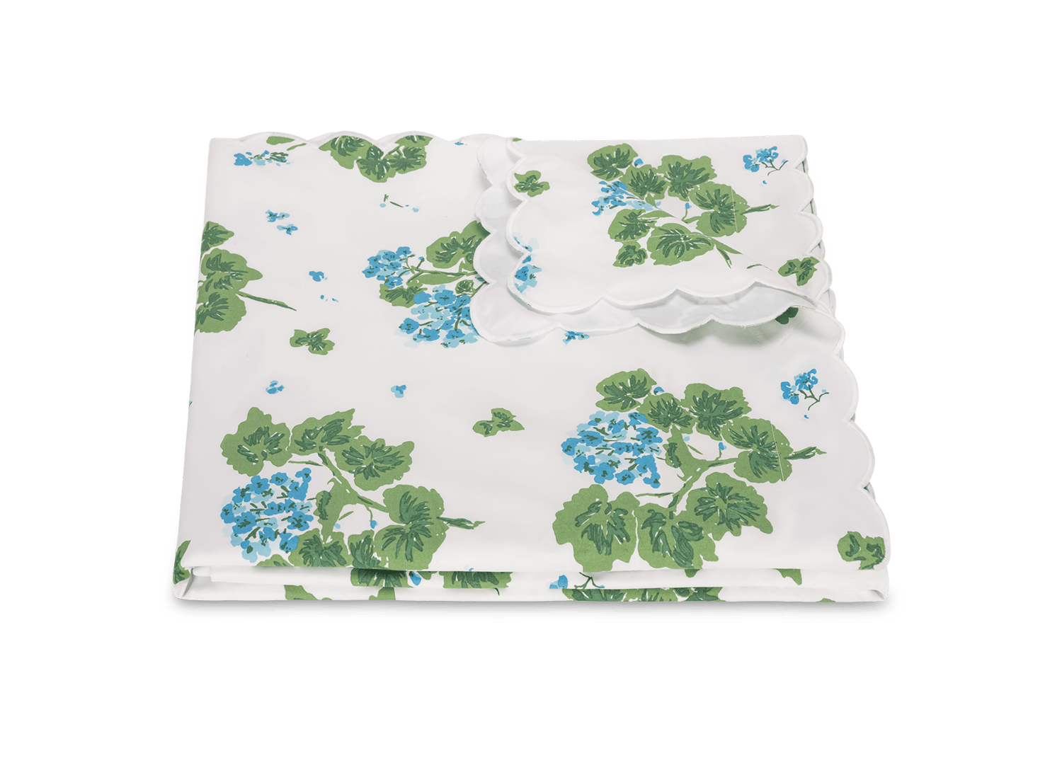 The Tillett x Matouk Geranium Bedding Collection in Blue by Matouk features a folded white percale set with green leaves, blue floral print, and scalloped edges, shown on a plain background.