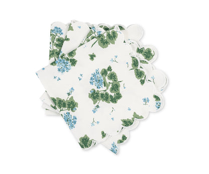 The Tillett x Matouk Blue Geranium napkin by Matouk features a white scalloped edge and green-blue floral pattern, making it ideal for accenting a floral table setting.