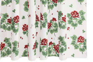 The Geranium Shower Curtain Collection by Matouk features a white backdrop with green leaves and red floral clusters, inspired by the Tillett design and repeated across crisp percale fabric.