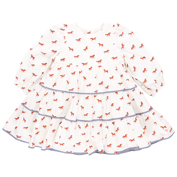 The Pink Chicken Girls' Julia Dress captures equestrian chic with its white long-sleeved design, showcasing chambray detailed tiers and delightful red horse prints on the tiered skirt.