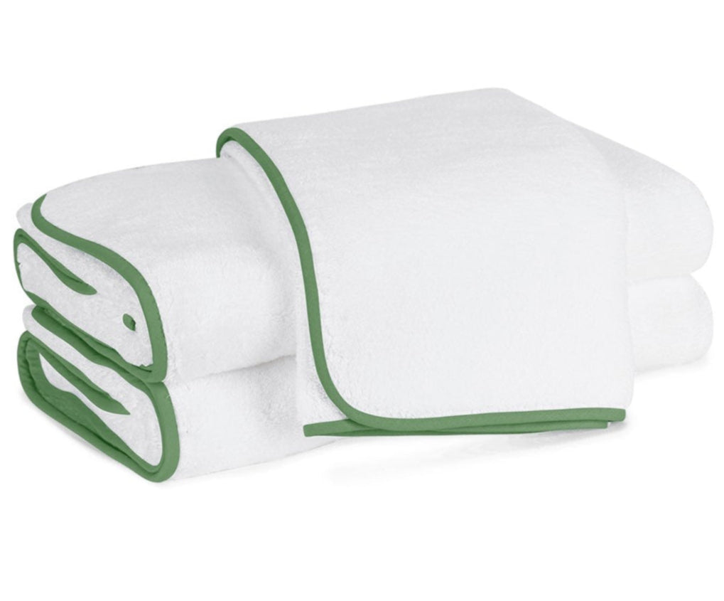 Two Matouk Giza Bath Collection towels, white with green borders and made from luxurious Egyptian cotton, are stacked neatly against a pristine white background.