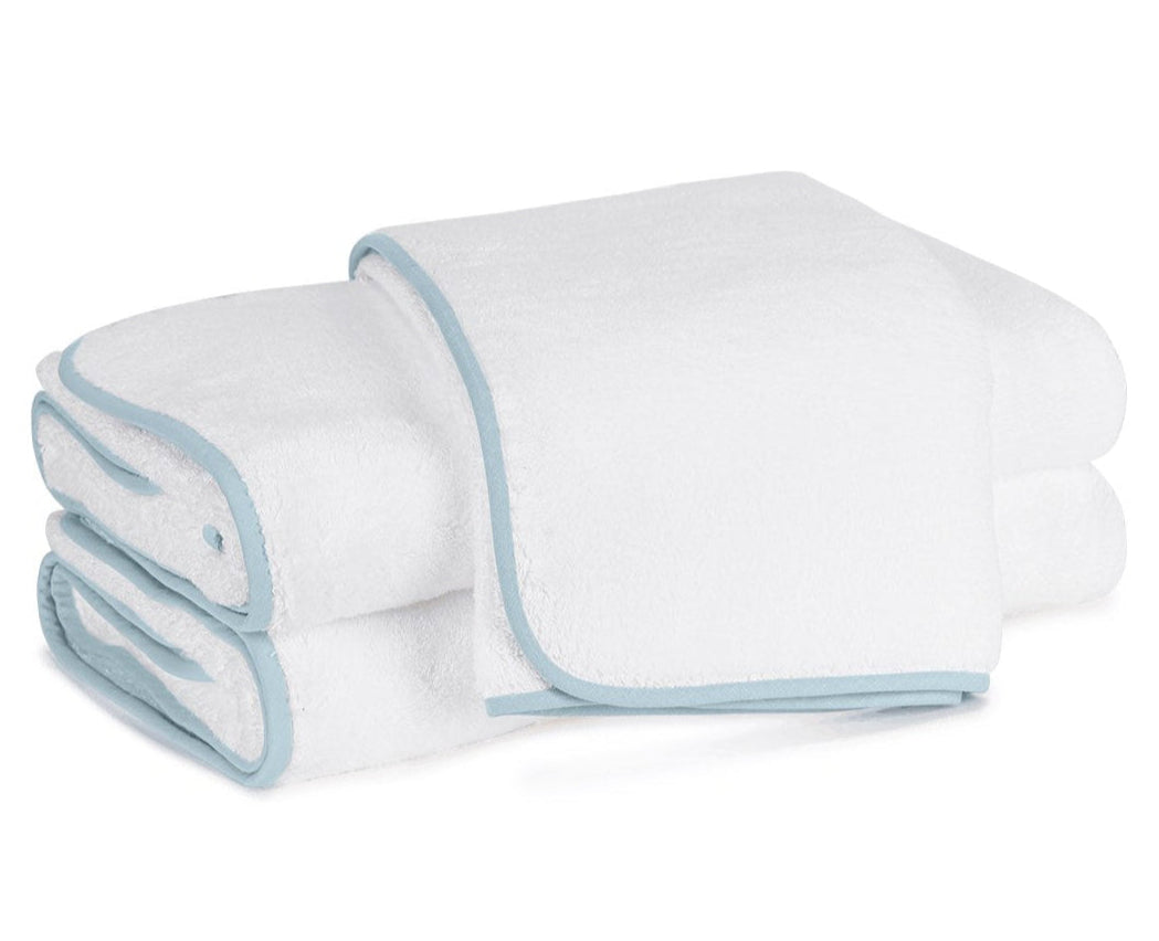 Two folded towels with light blue trim from the luxurious Matouk Giza Bath Collection are stacked neatly on a white background.
