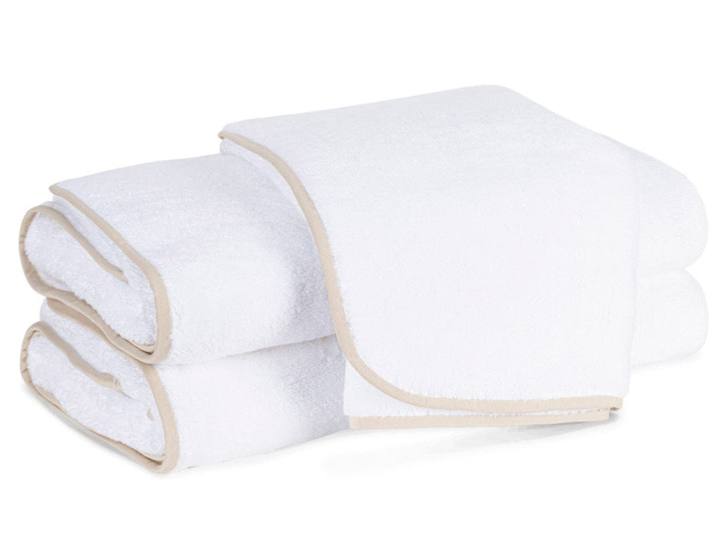 Two neatly folded towels from the Matouk Giza Bath Collection, crafted from luxurious Egyptian cotton and featuring an elegant beige trim, are stacked on a plain background.