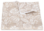 Experience the Granada Bedding Collection by Matouk—a beige and white folded blanket adorned with a botanical block print featuring delicate leaves, flowers, and subtle pomegranate motifs inspired by classic textile design.