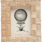The Grasse Frame Collection by Pigeon & Poodle features a rattan woven frame with an extra-thick profile, displaying a vintage hot air balloon illustration and a small red dog icon in the lower right corner.