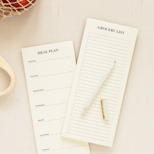 The Sugar Paper Magnetic ‘Meal Plan’ Notepad and grocery list notepad, paired with a white pen and cap, are displayed on a beige surface beside a reusable shopping bag—perfect for effortless weekly dinner planning.