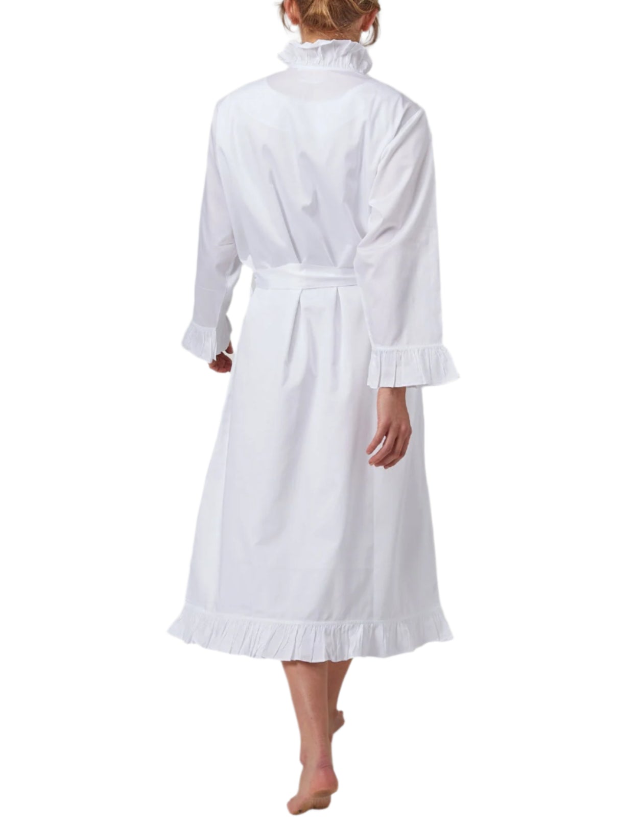 A person in the Haute Home Ruffle Robe, made from 100% white cotton sateen with ruffled cuffs and hem, stands barefoot and is seen from the back against a white background.