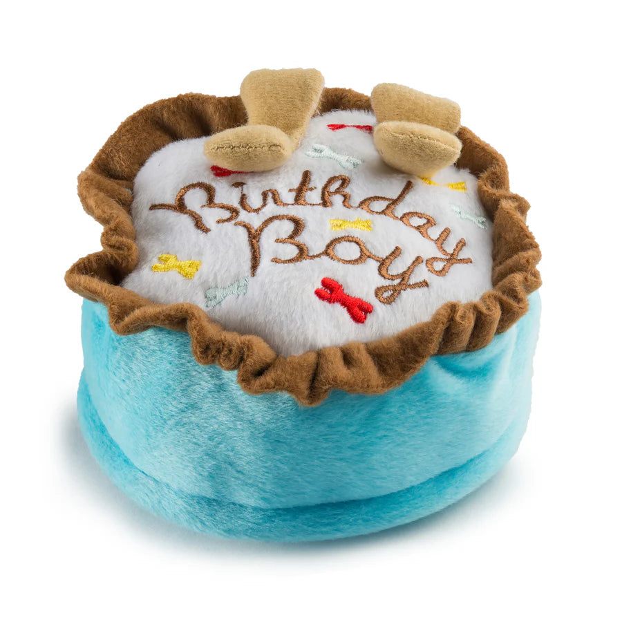The Haute Diggity Dog Birthday Boy Toy is a round, squeaky dog birthday cake toy with blue sides, brown trim, "Birthday Boy" embroidery, felt bones, and two bone-shaped accents.
