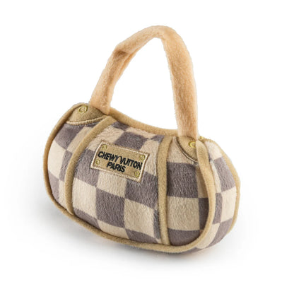 The Checker Chewy Vuiton Handbag by Haute Diggity Dog is a squeaky dog toy with a beige and gray checkered design and “Chewy Vuiton Paris” label, offering playful luxury for your pup.