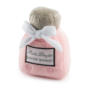 The Haute Diggity Dog Miss Dogior Perfume Bottle Dog Toy is a soft, pink plush shaped like a perfume bottle, complete with a white bow and "Miss Dogior Barking Bouquet" label.