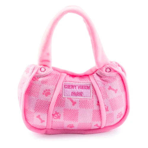 The Pink Chewy Vuiton Handbag by Haute Diggity Dog is a small, pink plush dog toy with checkered pattern, paw prints, and bones. The front label reads "CHEWY VUITON PARIS.