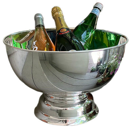 The Hôtel Silver Round Pedestal Chiller, a large silver-plate beverage cooler, elegantly displays and chills up to four bottles—wine, champagne, or sparkling water—on a gleaming reflective surface.