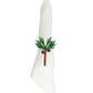 A white cloth napkin folded upright with an embroidered green palm tree and two coconuts on the front, elegantly accented by the Mercedes Salazar Coconut Palm Tree Napkin Ring, handmade in Colombia.