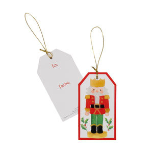 The Caspari Painted Nutcracker Hanging Tag set includes two rectangular tags with gold strings—one with a nutcracker design, the other with “To:” and “From:” in red—ideal for stylish gift-giving.