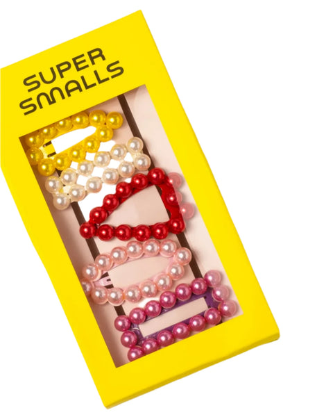 A yellow box labeled "Super Smalls Chit Chat Pearl Snap Clips" from the Super Smalls brand includes five stylish clips, each decorated with pearl-like beads in yellow, white, red, pink, and purple. These fashionable hair accessories can be used as pairs or stacked to create charming looks.