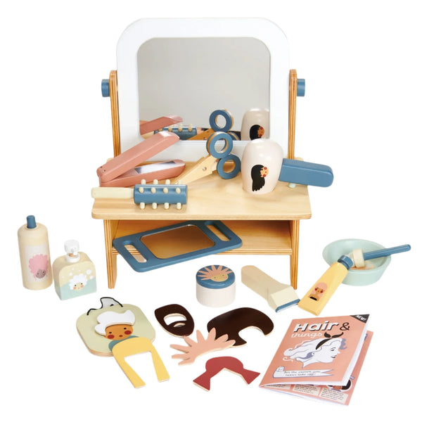 The Tender Leaf Hair Salon by Tender Leaf Toys is a children's pretend play set that includes a mirror, scissors, comb, hairdryer, and brush, all neatly displayed on a petite shelf. This set offers endless styling possibilities for young imaginations.