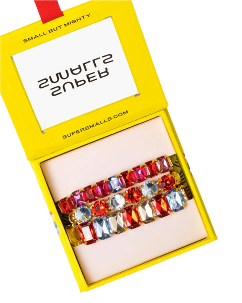 A Super Smalls Happy Hour Bracelet Set, featuring three vibrant gemstone bracelets, beautifully arranged in a yellow box. The lid of the box is adorned with the text "SMALL BUT MIGHTY" and "SUPERSMALLS." These stackable pieces from Super Smalls are perfect for adding a pop of color to any outfit.