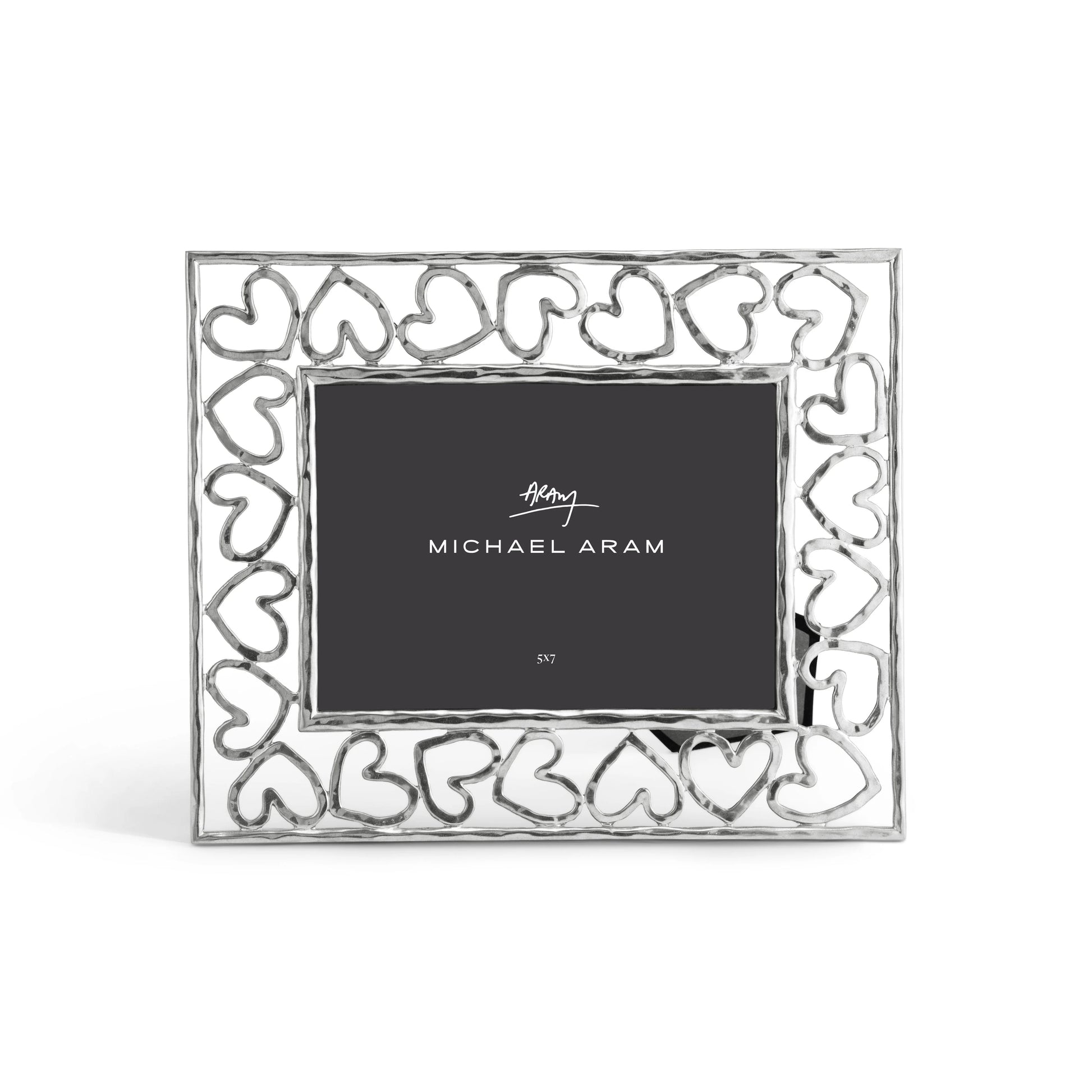 The Michael Aram Heart Frame, from the Heart Collection, is a rectangular silver picture frame featuring an open heart pattern border and displays a placeholder card labeled "Michael Aram.