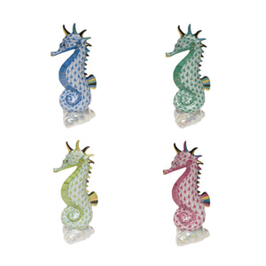 Four Herend Sea Horse figurines in blue, green, yellow, and pink with hand-painted designs and gold accents are arranged in a grid on a white background.