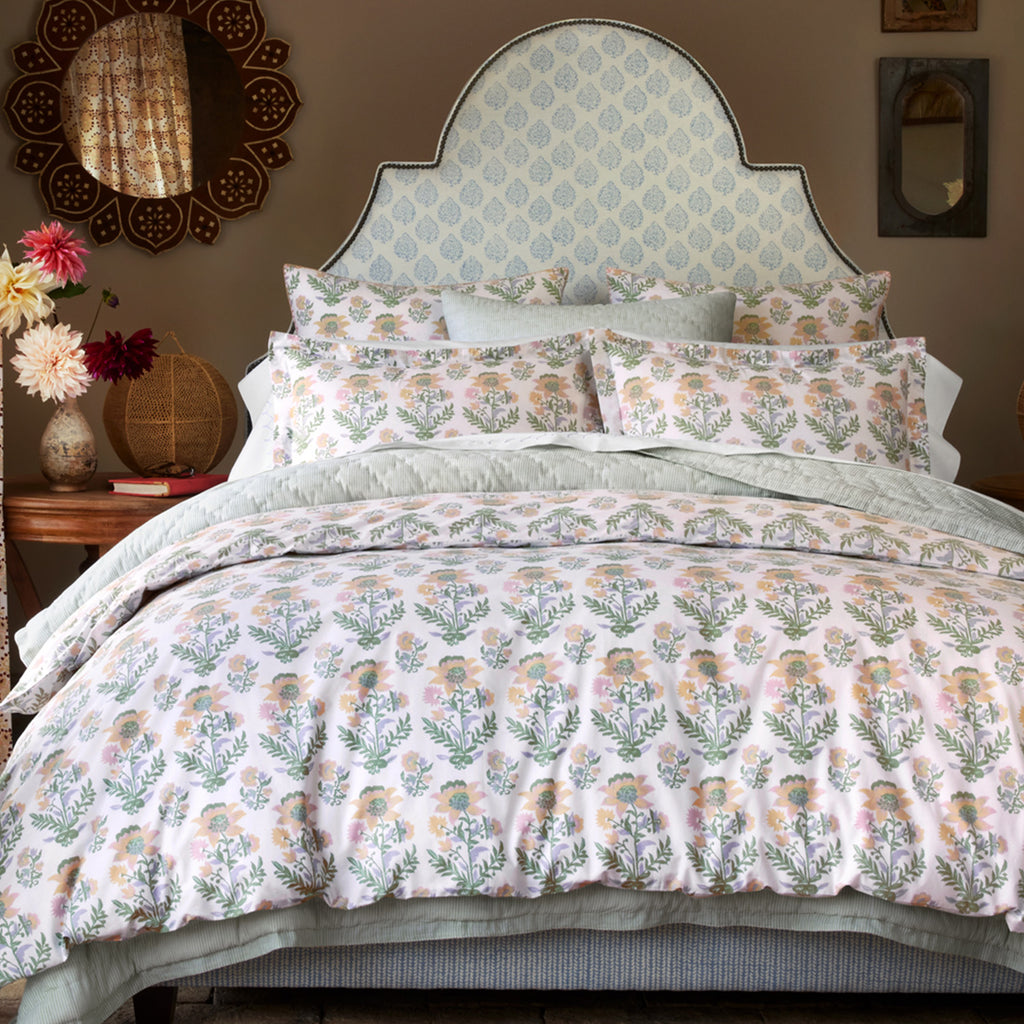 A peaceful setting features the John Robshaw Hina Sham: bedding with a soft pastel floral print and light blue accents, crafted from smooth 200 thread count organic cotton. Bedside tables and decor complete the look.