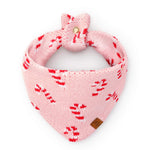 Pink Candy Canes Knit Dog Bandana in pink knit with a red and white candy cane pattern, featuring a tied top and a The Foggy Dog leather-look brand tag.