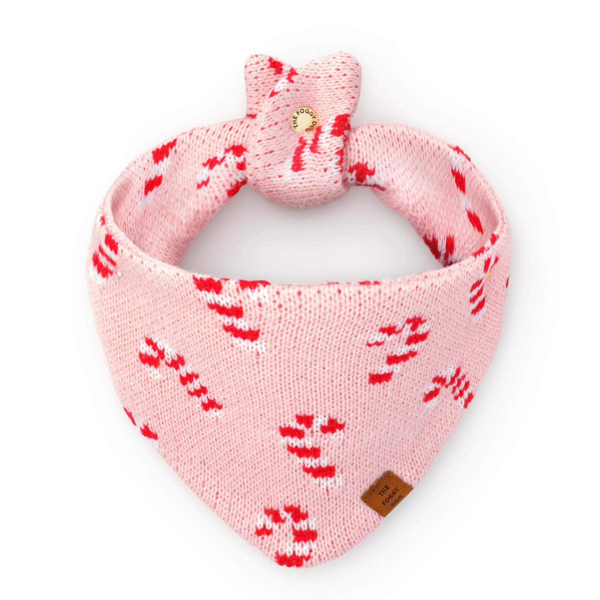 Pink Candy Canes Knit Dog Bandana in pink knit with a red and white candy cane pattern, featuring a tied top and a The Foggy Dog leather-look brand tag.