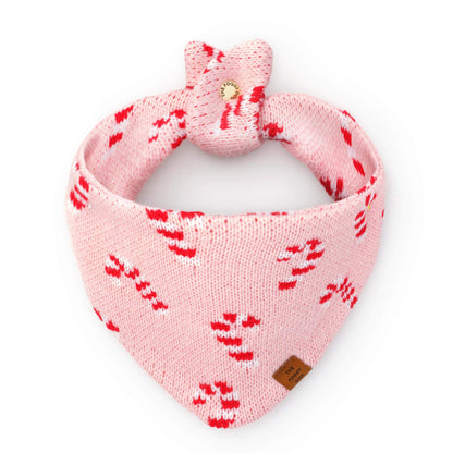 Pink Candy Canes Knit Dog Bandana in pink knit with a red and white candy cane pattern, featuring a tied top and a The Foggy Dog leather-look brand tag.