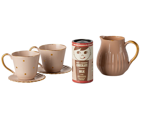 The Maileg Hot Chocolate Set, Mini is a delightful addition to the Teddy family's afternoon tea rituals. It includes two charming cups with saucers, a can of chocolate-flavored milk, and a brown pitcher with a handle.