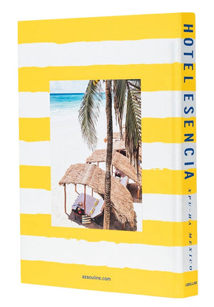 The book named "Hotel Esencia" by Assouline has a cover adorned with yellow and white stripes, showcasing a beach scene photograph that includes palm trees and straw beach huts. This captivating image subtly hints at the understated luxury synonymous with Hotel Esencia in Riviera Maya.