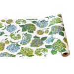 The Paper Runner Collection by Hester & Cook features wrapping paper with blue, yellow, and green hydrangea flowers on white—ideal for standout gift wrap or as a creative table runner in your dining area.