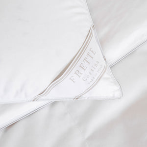 Close-up of a white Cortina Medium Density Pillow Insert by Frette, showing a corner with a Frette label.