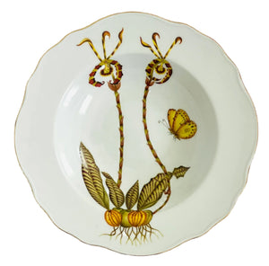 The Orchid I Dinnerware Collection by Anna Weatherley features a white porcelain plate, hand painted with two stylized plants, green leaves, yellow bulbs, and a yellow butterfly on the right side.
