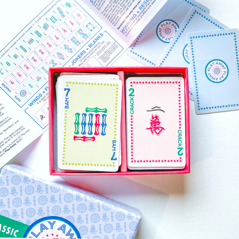 The Play Away Cards Mahjong Playing Cards come in a red box, include an instruction sheet, and feature cards laid out for easy viewing—ideal for beginners wanting quick, enjoyable games.