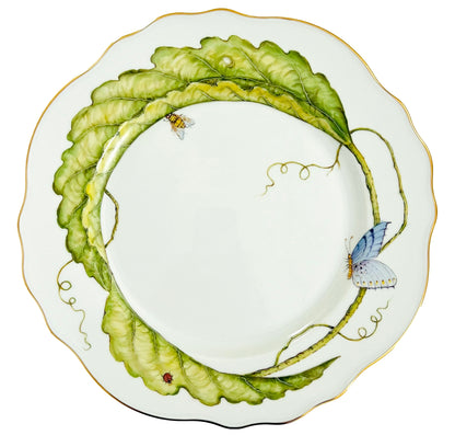 Hand-painted by Anna Weatherley, this Garden Leaves Dinnerware Collection plate features wavy white porcelain, green leaves, a butterfly, bee, ladybug, and a thin gold rim.
