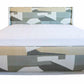 The Highland House Gustav Bed, King, is a modern masterpiece with an upholstered headboard and footboard, showcasing a geometric pattern in shades of gray, green, and beige, complemented by subtle wood details and pristine white bedding.