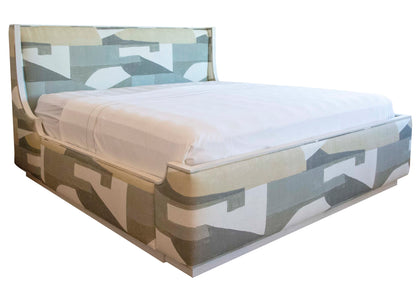 The Highland House Gustav Bed, King features a modern design with a geometric-patterned, upholstered headboard and base. It showcases a lightly colored abstract design, enhanced by elegant wood details and complemented by crisp white bedding.