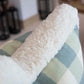 A close-up of a fluffy white blanket draped over the Hive Custom Pillows Small Check Blue Pillow.