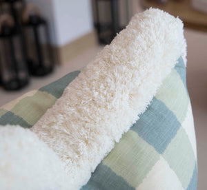 A close-up of a fluffy white blanket draped over the Hive Custom Pillows Small Check Blue Pillow.