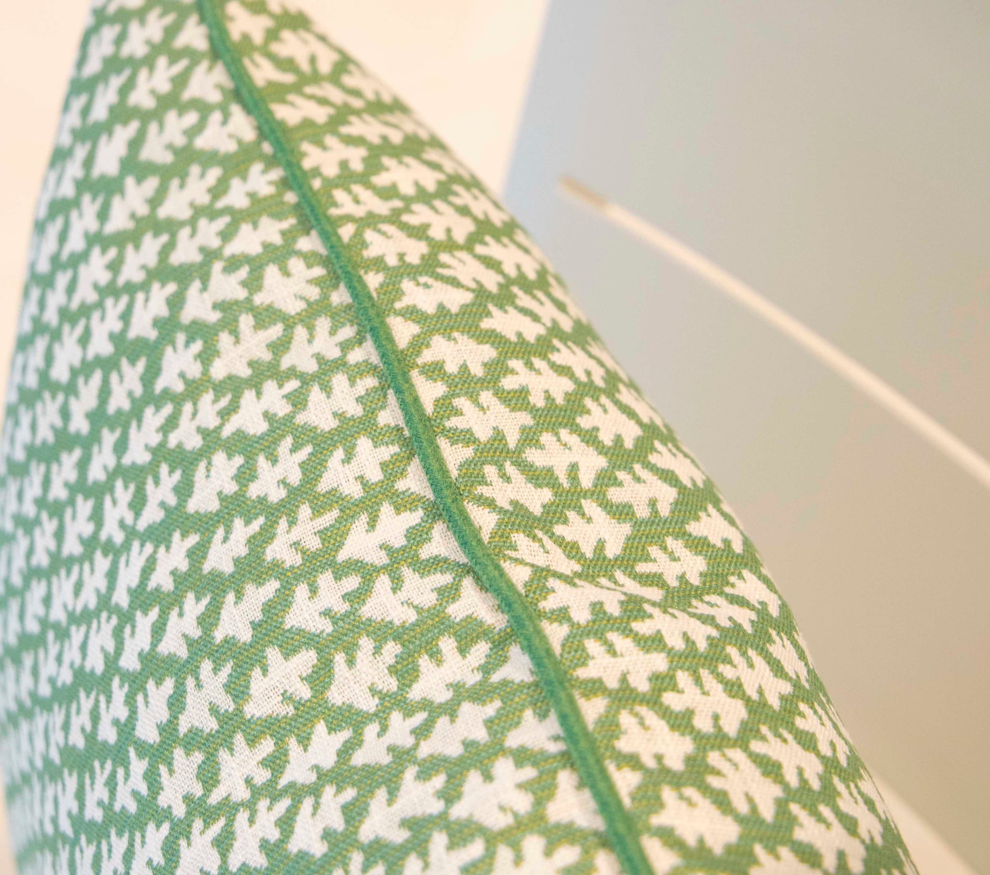 Close-up of the 22" x 22" Burma Meadow Outdoor Pillow by Hive Custom Pillows, featuring green fabric with a white leaf pattern and green piping along the edge.