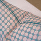 Close-up of the Boheme Pink and Celadon Pillow by Hive Custom Pillows, featuring blue and pink circular patterns with visible piping, handmade in the USA and shown against a neutral background.