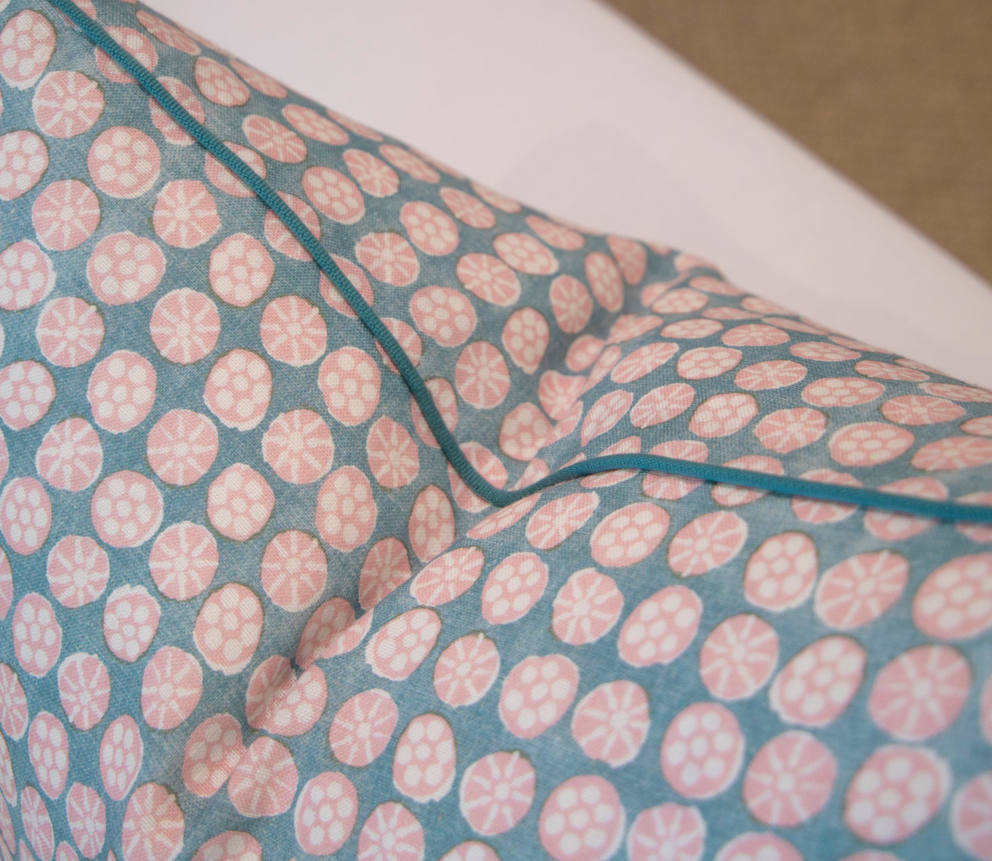 Close-up of the Boheme Pink and Celadon Pillow by Hive Custom Pillows, featuring blue and pink circular patterns with visible piping, handmade in the USA and shown against a neutral background.