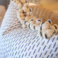 Close-up of the Little Bamboo Navy Pillow by Hive Custom Pillows, a handmade down-filled pillow with a blue dashed pattern and cream pom-pom trim, resting next to a woven basket.