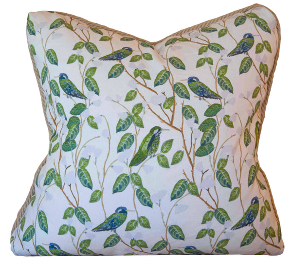 The Hummingbirds White Pillow by Associated Design features a handmade square cushion adorned with blue and green birds on leafy branches.