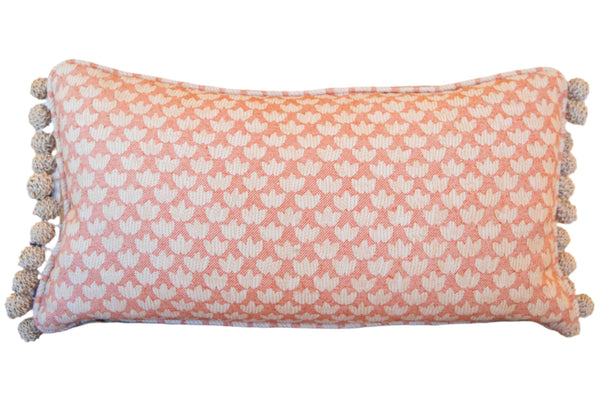 The Associated Design's Eythorne Eyth Lumbar Pillow is a handmade, rectangular pink and white pillow featuring a tassel fringe along its edges.