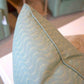 Close-up of the Ondine Soft Green Pillow by Hive Custom Pillows, featuring a wavy stitched pattern and displayed on a white surface in a living room.