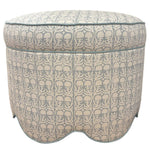 The Suzie Scalloped Ottoman by Highland House features beige and blue patterned fabric, a scalloped base, and piped edges. Use this versatile piece as extra seating or a chic footrest in any room.